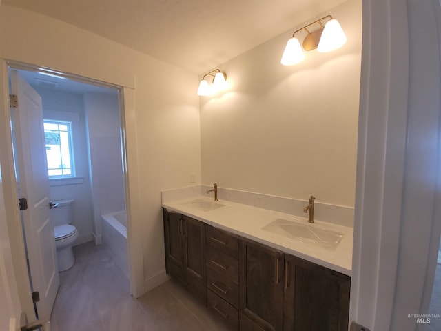 bathroom featuring a tub, toilet, double vanity, and a sink