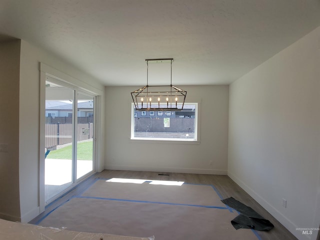 unfurnished dining area with wood finished floors and baseboards
