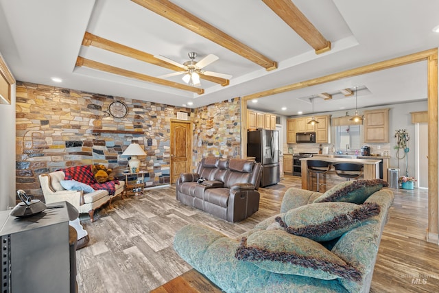 living room featuring ceiling fan, wood-type flooring, and a tray ceiling