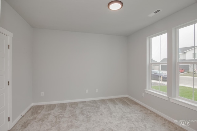 spare room with visible vents, light carpet, and baseboards