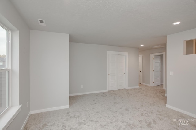 spare room with baseboards, visible vents, and light colored carpet