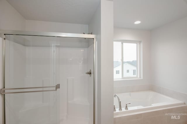 full bath featuring a textured ceiling, a stall shower, and a bath