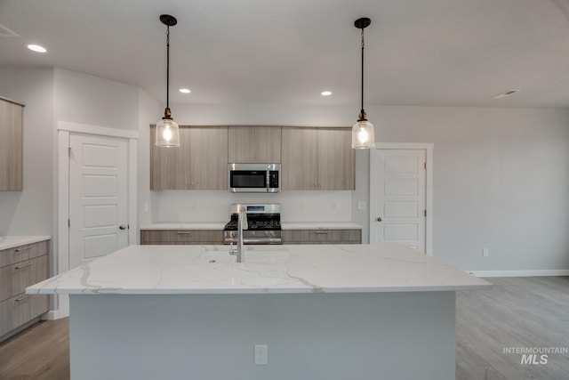 kitchen with stainless steel appliances, a kitchen island with sink, and light brown cabinetry