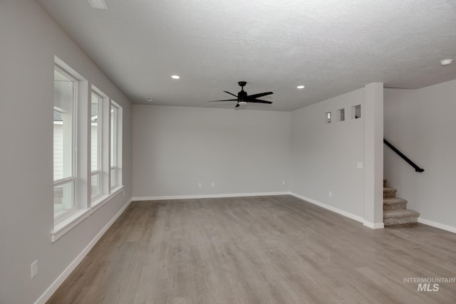 unfurnished room featuring baseboards, stairway, a textured ceiling, light wood-type flooring, and recessed lighting