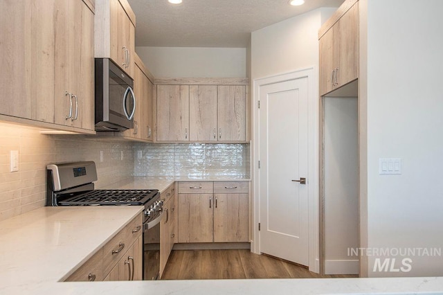 kitchen with light brown cabinetry, stainless steel appliances, light hardwood / wood-style flooring, and tasteful backsplash