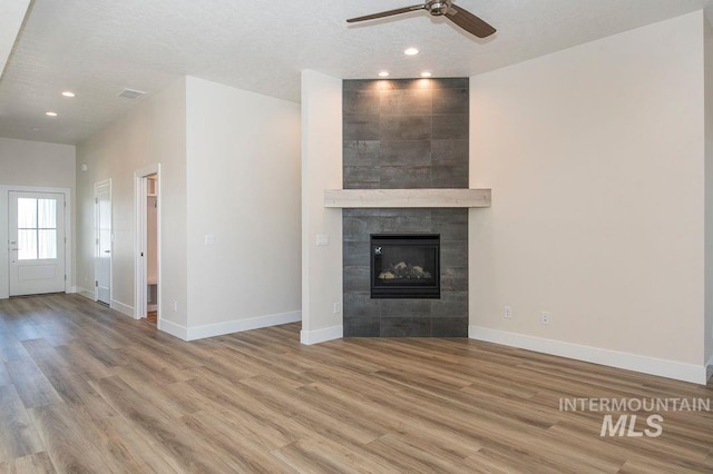 unfurnished living room with a fireplace, hardwood / wood-style floors, a textured ceiling, and ceiling fan