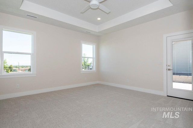 spare room with carpet floors, a raised ceiling, and ceiling fan