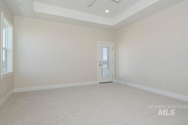 carpeted spare room with a tray ceiling