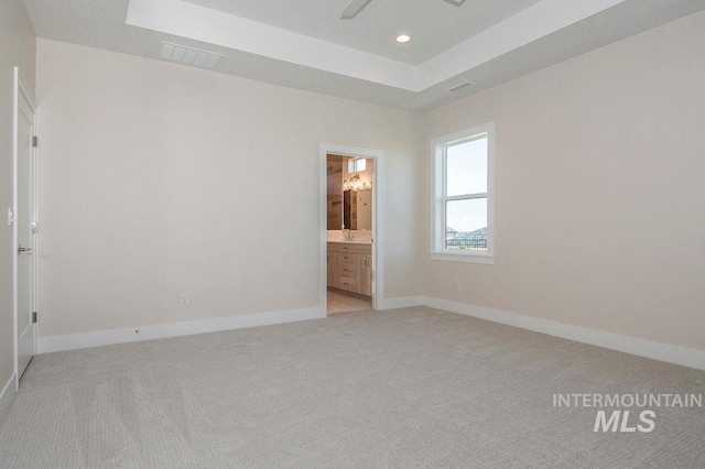 carpeted spare room with a raised ceiling