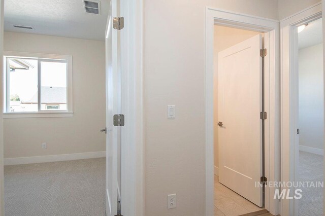 hall with light colored carpet