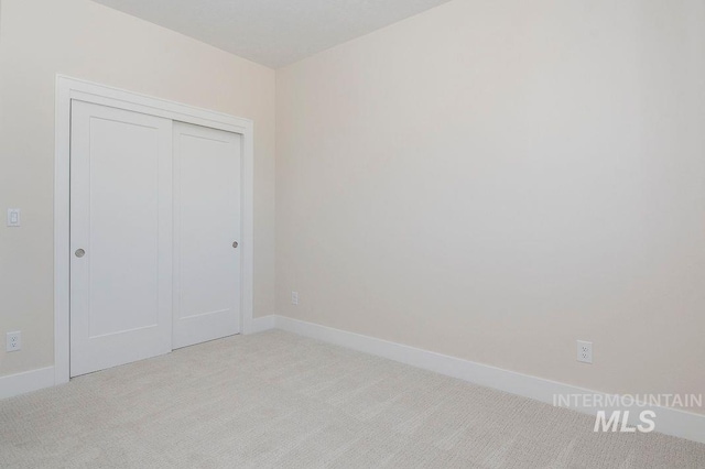 unfurnished bedroom featuring light colored carpet and a closet