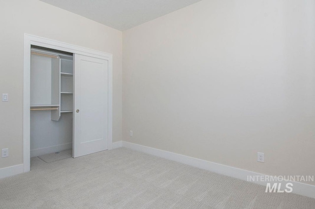 unfurnished bedroom with light carpet and a closet