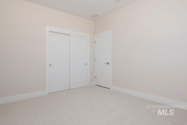 unfurnished bedroom with light carpet and a closet