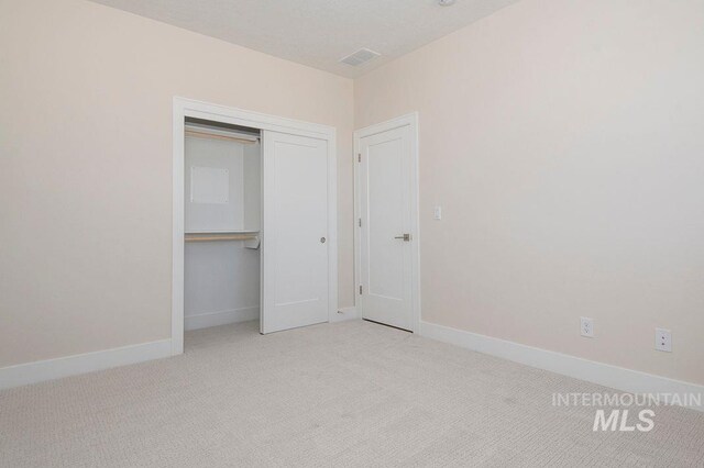 unfurnished bedroom with light carpet and a closet