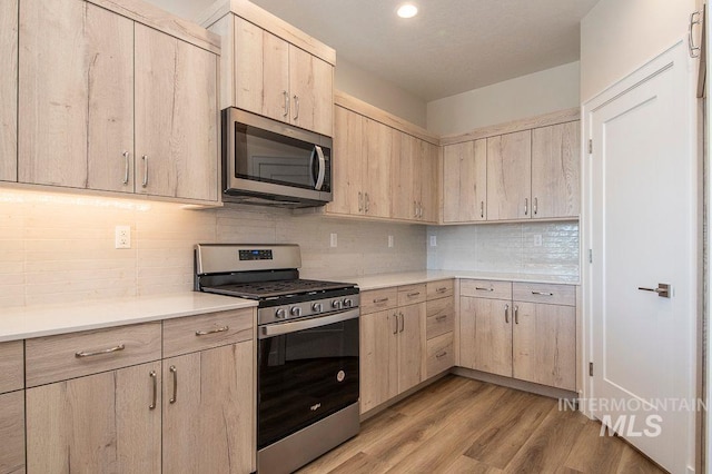 kitchen featuring appliances with stainless steel finishes, backsplash, light hardwood / wood-style floors, and light brown cabinetry