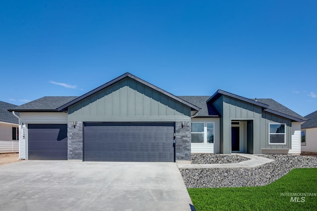 view of front facade with a shingled roof, board and batten siding, driveway, and a garage