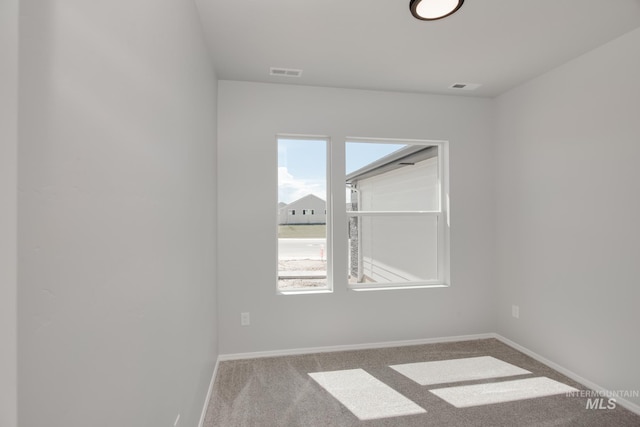 empty room featuring baseboards, visible vents, and carpet
