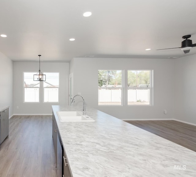 kitchen with baseboards, light countertops, light wood finished floors, and a sink