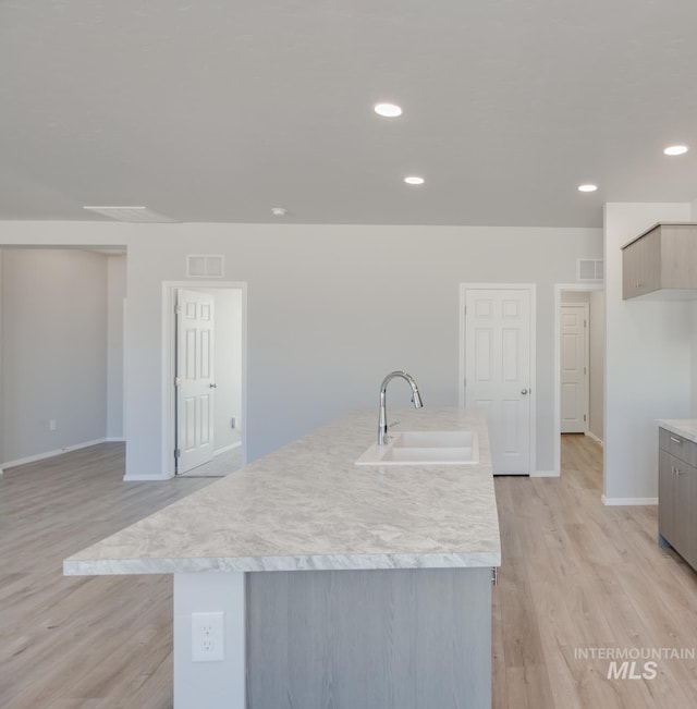 kitchen with light wood-style flooring, baseboards, visible vents, a sink, and light countertops