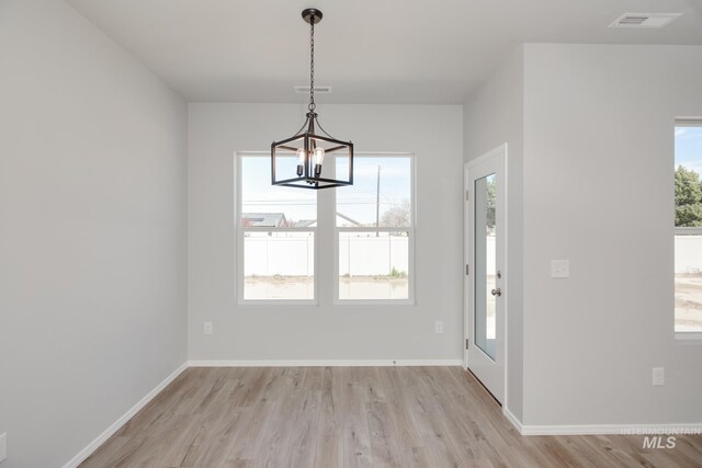 foyer with light wood finished floors, a chandelier, baseboards, and visible vents