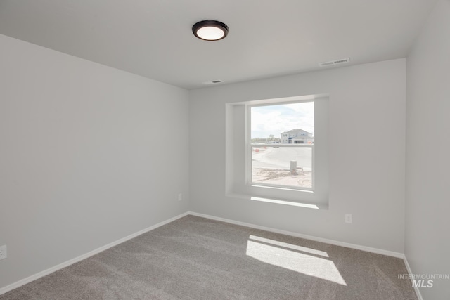 empty room featuring carpet flooring, baseboards, and visible vents