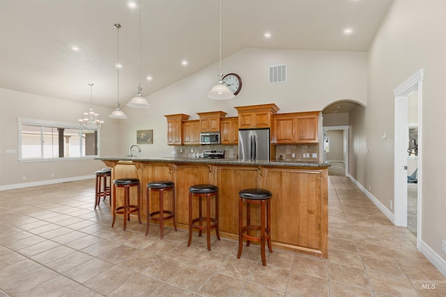 2790 S Mcdermott Rd, Nampa, ID 83687 - kitchen with stainless steel appliances, brown cabinetry, a kitchen breakfast bar, a sink, and tasteful backsplash