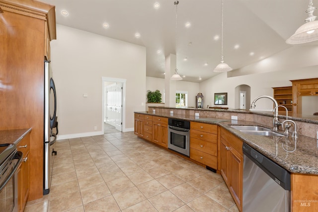 2790 S Mcdermott Rd, Nampa, ID 83687 - kitchen featuring appliances with stainless steel finishes, a sink, brown cabinetry, light tile patterned flooring, and dark stone counters
