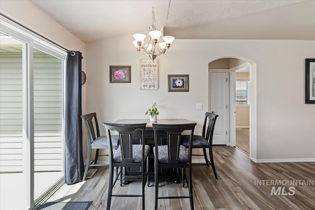 3918 Fallwood Cir, Caldwell, ID 83607 - dining room with arched walkways, lofted ceiling, a chandelier, wood finished floors, and baseboards