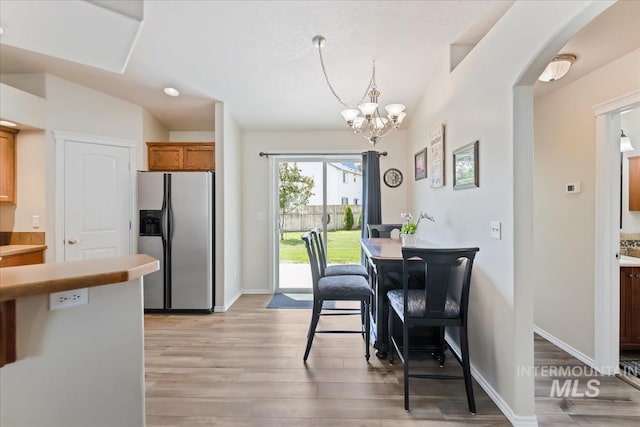 3918 Fallwood Cir, Caldwell, ID 83607 - dining area with light wood-style floors, arched walkways, a chandelier, and baseboards