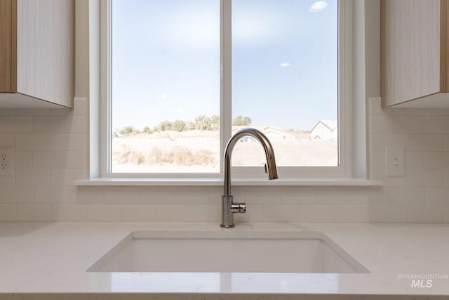 details with light stone countertops, sink, backsplash, and light brown cabinetry