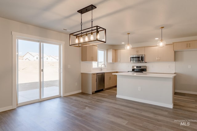 kitchen featuring light hardwood / wood-style flooring, stainless steel appliances, a center island, decorative backsplash, and decorative light fixtures