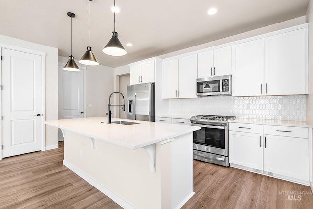 kitchen featuring stainless steel appliances, light countertops, and a kitchen island with sink