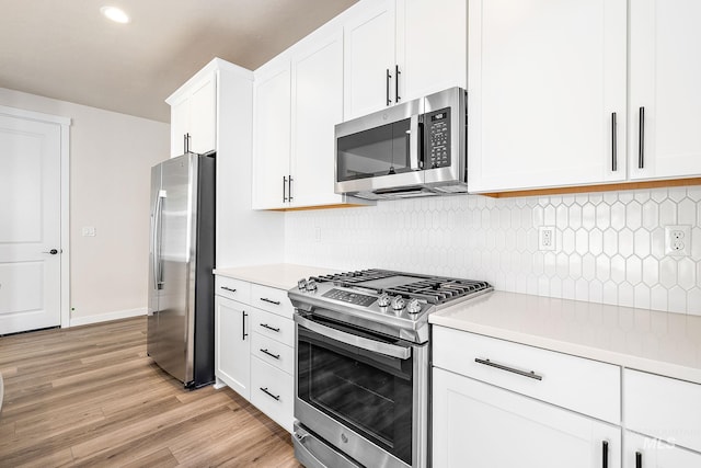 kitchen featuring tasteful backsplash, stainless steel appliances, light countertops, light wood-style floors, and white cabinetry