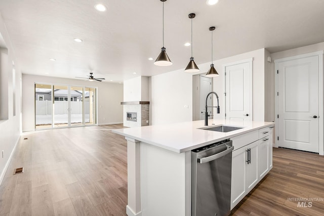 kitchen featuring pendant lighting, a center island with sink, open floor plan, white cabinets, and dishwasher