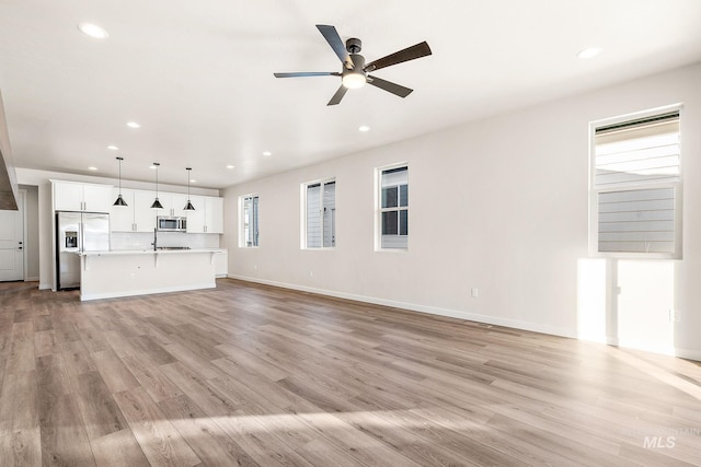 unfurnished living room featuring light wood finished floors, baseboards, a ceiling fan, and recessed lighting