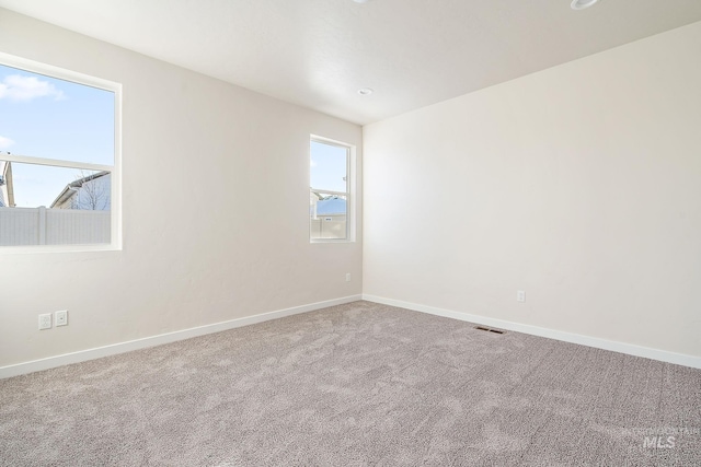 carpeted empty room with visible vents and baseboards