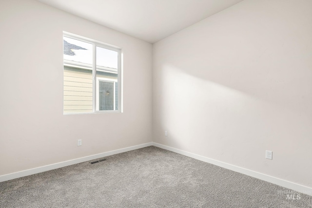 empty room with carpet, visible vents, and baseboards