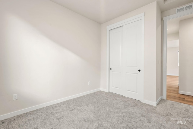 unfurnished bedroom featuring baseboards, a closet, visible vents, and carpet flooring