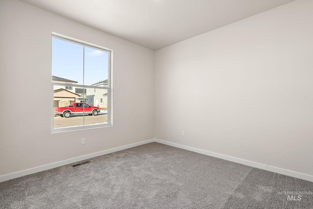 carpeted spare room featuring baseboards and visible vents