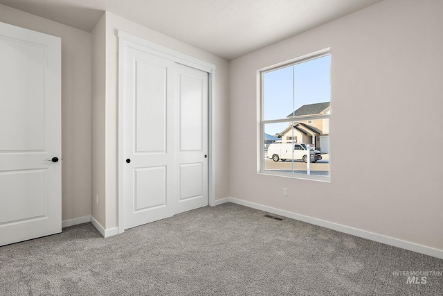 unfurnished bedroom with baseboards, visible vents, a closet, and light colored carpet