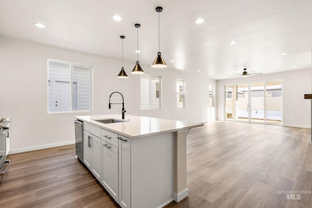 kitchen featuring a sink, open floor plan, light countertops, dishwasher, and decorative light fixtures