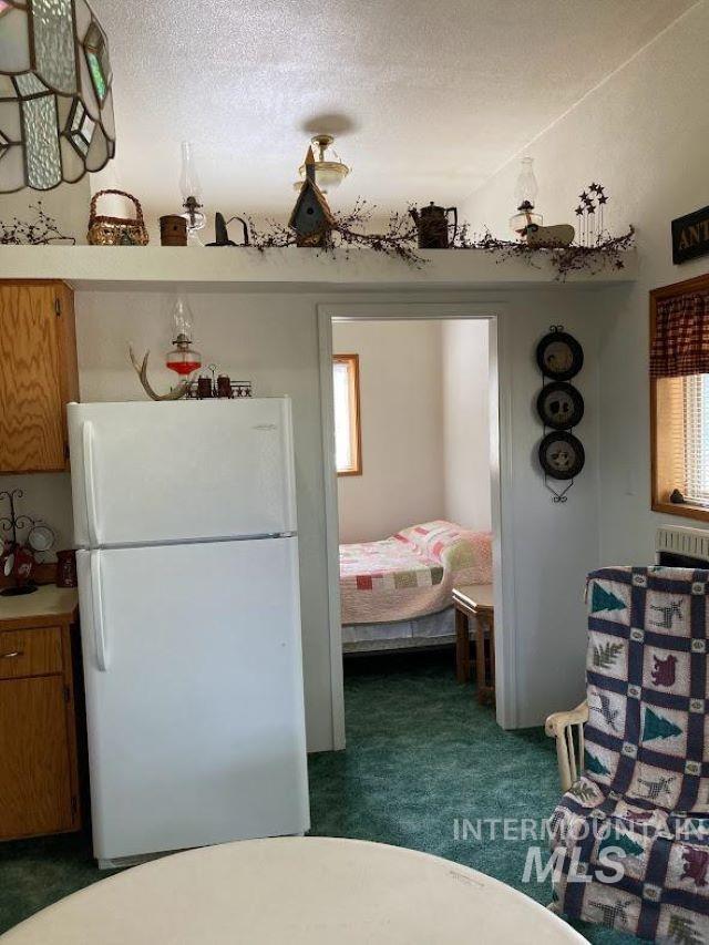 kitchen featuring dark colored carpet, a textured ceiling, and white refrigerator