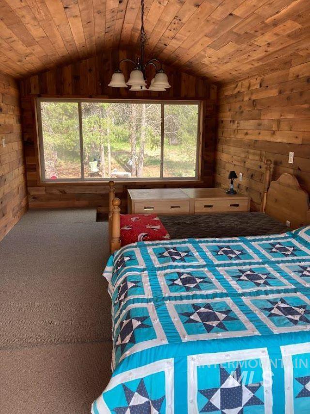 bedroom with multiple windows, wood ceiling, and wooden walls