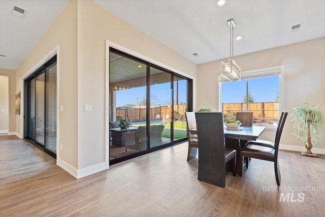 dining area with visible vents, a healthy amount of sunlight, and wood finished floors