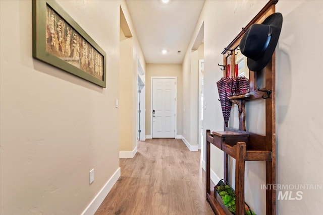 corridor with baseboards and light wood finished floors