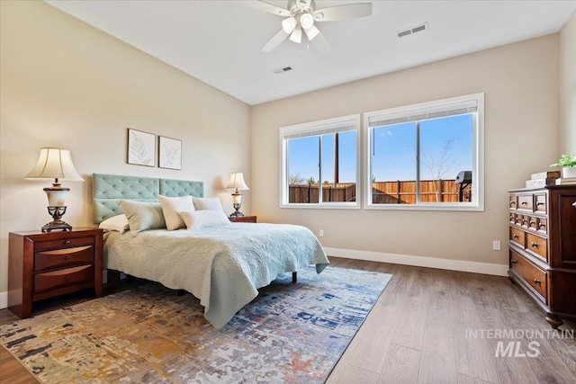 bedroom featuring visible vents, ceiling fan, baseboards, and wood finished floors