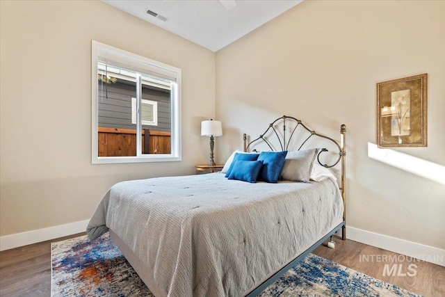 bedroom with visible vents, baseboards, and wood finished floors