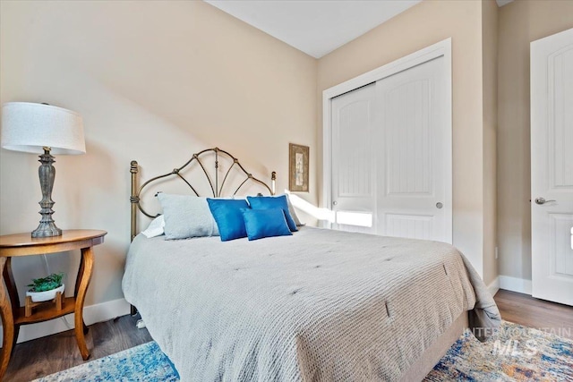 bedroom with wood finished floors, a closet, and baseboards