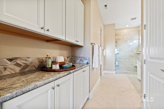 kitchen with visible vents, baseboards, light stone countertops, marble finish floor, and white cabinetry