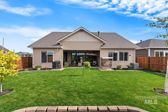 rear view of property featuring a patio, a fenced backyard, central AC, a lawn, and board and batten siding